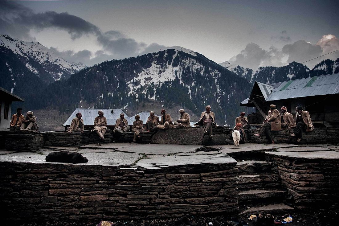 Elder men in the traditional wool suit sit in the village square near the temple. They are the first generation of people who started to cultivate the infesting strain that was growing wild in the Himalayas