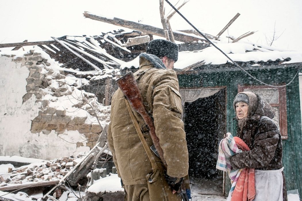 UKRAINE. Shahanov, East Ukraine. November 30, 2014. A young Cossack soldier greets 86-year old Cossack woman whose home had recently been destroyed by Ukrainian Army shelling in the separatist stronghold.