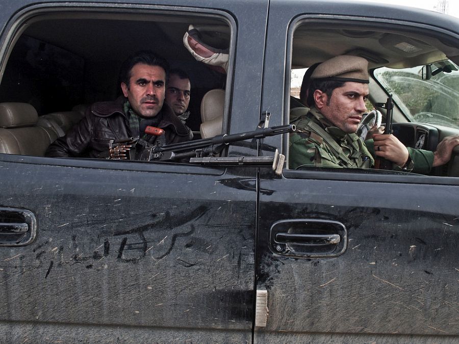 IRAQ. Dokuk, Kirkuk Province. December 3, 2014. Kurdish Peshmerga fighters drive through an Arab village recently captured from the Islamic State near the front line about 30Km south of the city of Kirkuk.