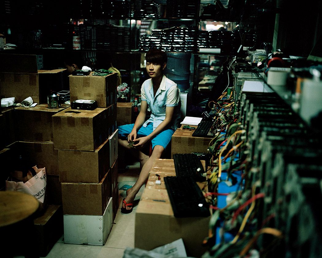 Guangzhou, China A boy waits for customers in his hardware materials store, inside a big shopping mall for electronics. They sell mostly used materials which can then be used to compose "new" second-hand electronic items.