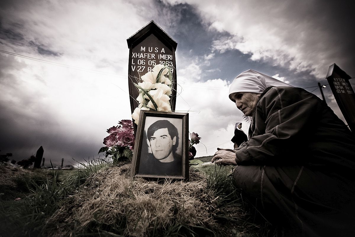 A Kosovar woman prays at the grave of her son was killed during the war. The son's body was found in a mass grave not far from Krusa e Madhe